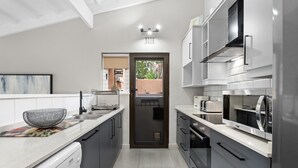 A modern kitchen with grey cabinets, stainless steel appliances, and a dishwasher. - San Lameer Villa 2412 (Southbroom)