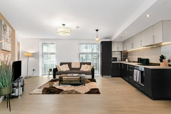 Enjoy a city view from the living area, featuring a sofa set and coffee table, and a well-equipped kitchen with a sleek island.
