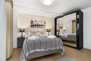 Relax in a serene space with a large bed, bedside tables, and a large mirror.