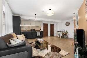 Contemporary living space with a kitchen, dining area, and living room featuring a sofa and coffee table.