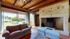 Una sala de estar acogedora con chimenea de piedra, un sofá de cuero y un ventanal con vistas al exterior.
