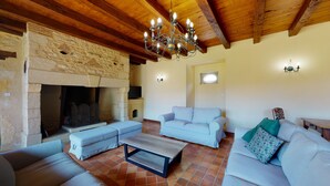 Una sala de estar acogedora con paredes de piedra, chimenea y techo de madera. Hay dos sofás y una mesa de centro.