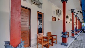 Un pasillo con puertas de madera, piso de baldosas y una fila de sillas.