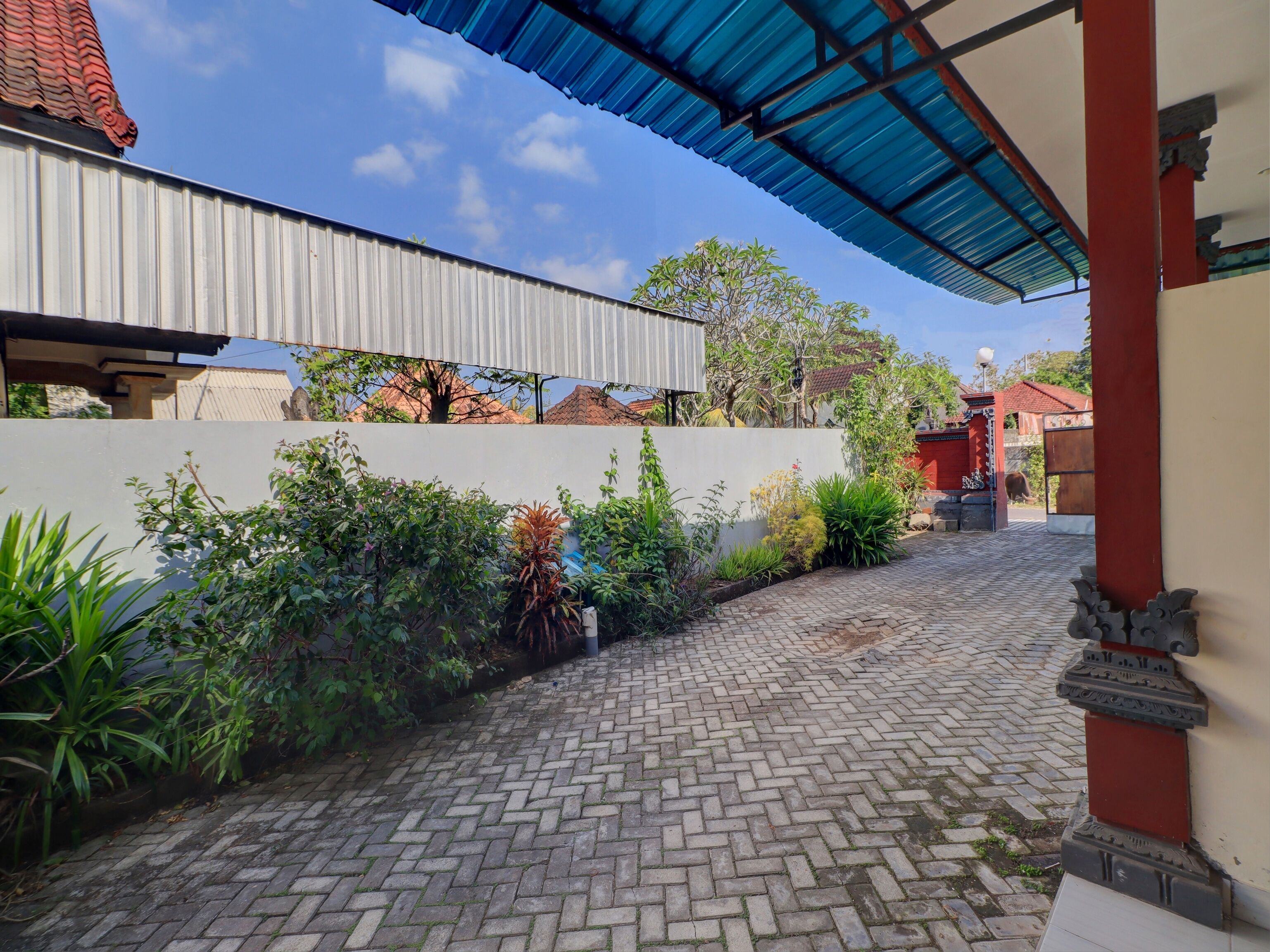 A paved pathway leading to a building with a corrugated metal roof.