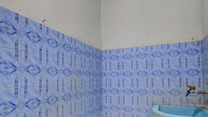 Un baño con baldosas azules estampadas, una bañera azul y un inodoro.