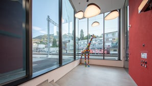 A giraffe statue in a modern lobby with large windows, a red wall, and a staircase. - The Freddie Mercury Hotel (Montreux)