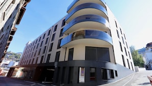A modern building with a curved facade, multiple balconies, and large windows. - The Freddie Mercury Hotel (Montreux)