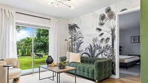 A modern living room with a green sofa, a coffee table, and a large window with a view of a garden.