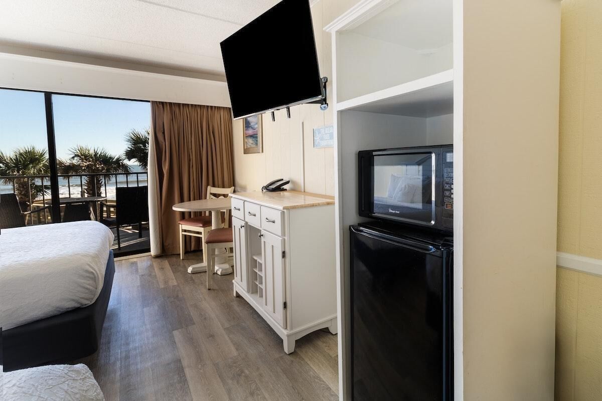 Une chambre d’hôtel comprenant un lit, un bureau avec une chaise, une télévision et un réfrigérateur.