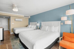 Une chambre d’hôtel avec deux lits, un ventilateur de plafond, un appareil de climatisation, un bureau et une chaise.