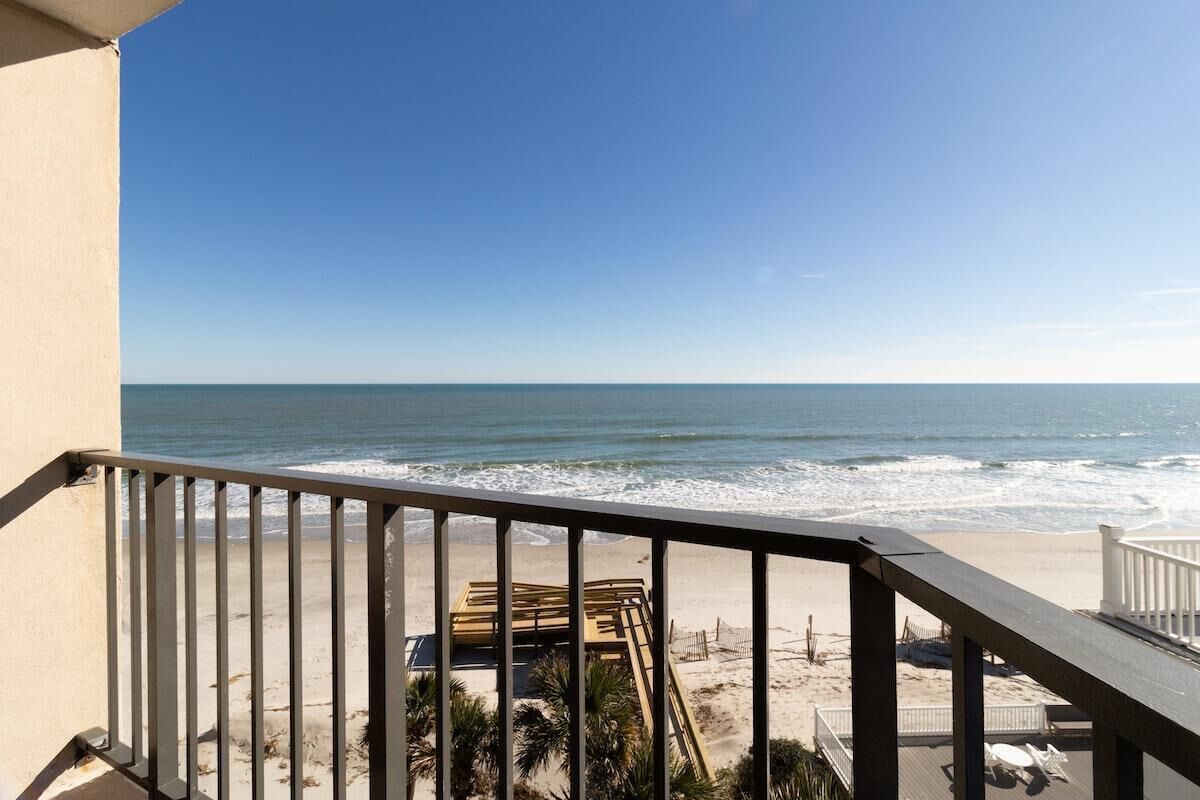 Ein Balkon mit Blick auf den Ozean und den Strand.