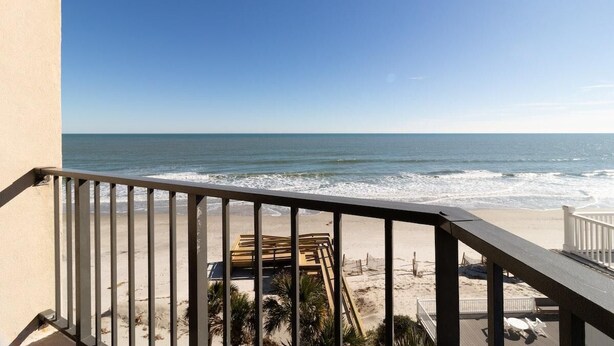Un balcon avec vue sur l’océan et la plage.