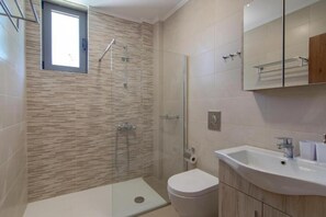 A modern bathroom with a shower, toilet, and sink.