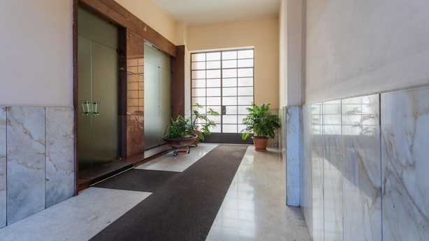 A hallway with a marble floor, potted plants, and a large window. - Monte Grappa Apartment by Wonderful Italy (Turin)