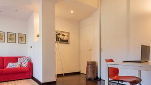 A modern living room with a red sofa, a small wooden stool, and a desk with a laptop. - Monte Grappa Apartment by Wonderful Italy (Turin)