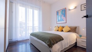 A bedroom with a bed, bedside table, and a window with curtains. - Monte Grappa Apartment by Wonderful Italy (Turin)