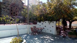 Un patio con muro de piedra, un árbol pequeño y una mesa con sillas.