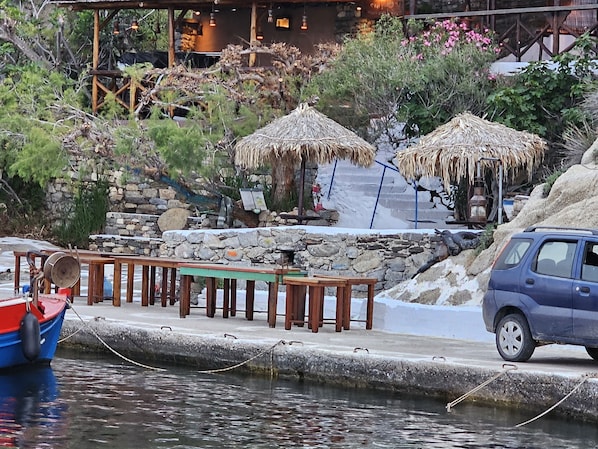 Un muelle con un bote, un muro de piedra y un coche aparcado cerca.
