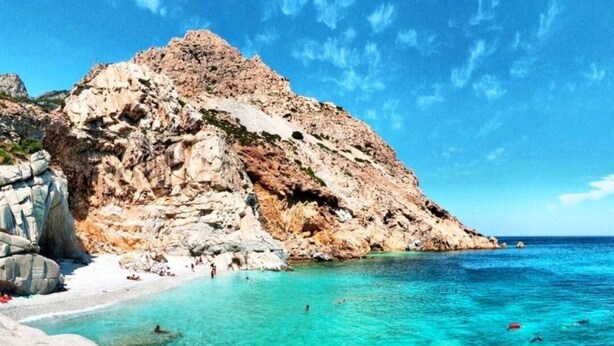 Una costa rocosa con aguas turquesas cristalinas y una playa de arena.