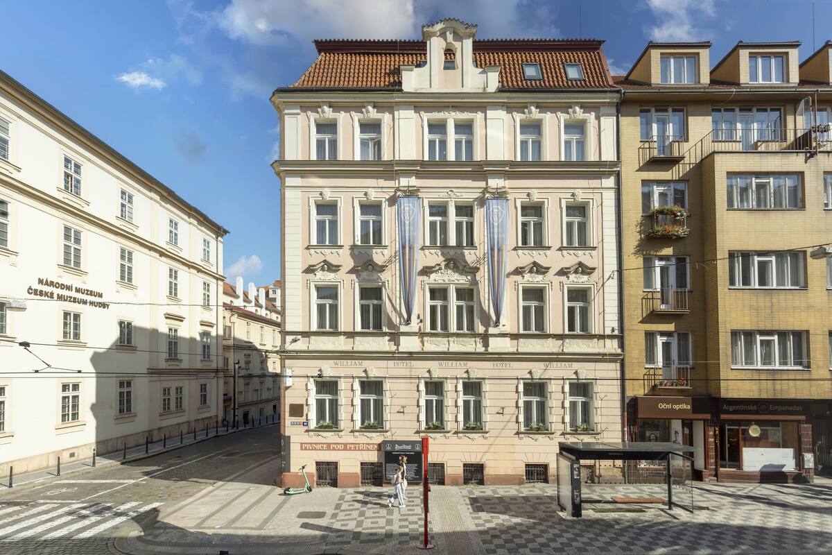 A historic building with multiple windows, a central entrance, and a checkered pavement area.