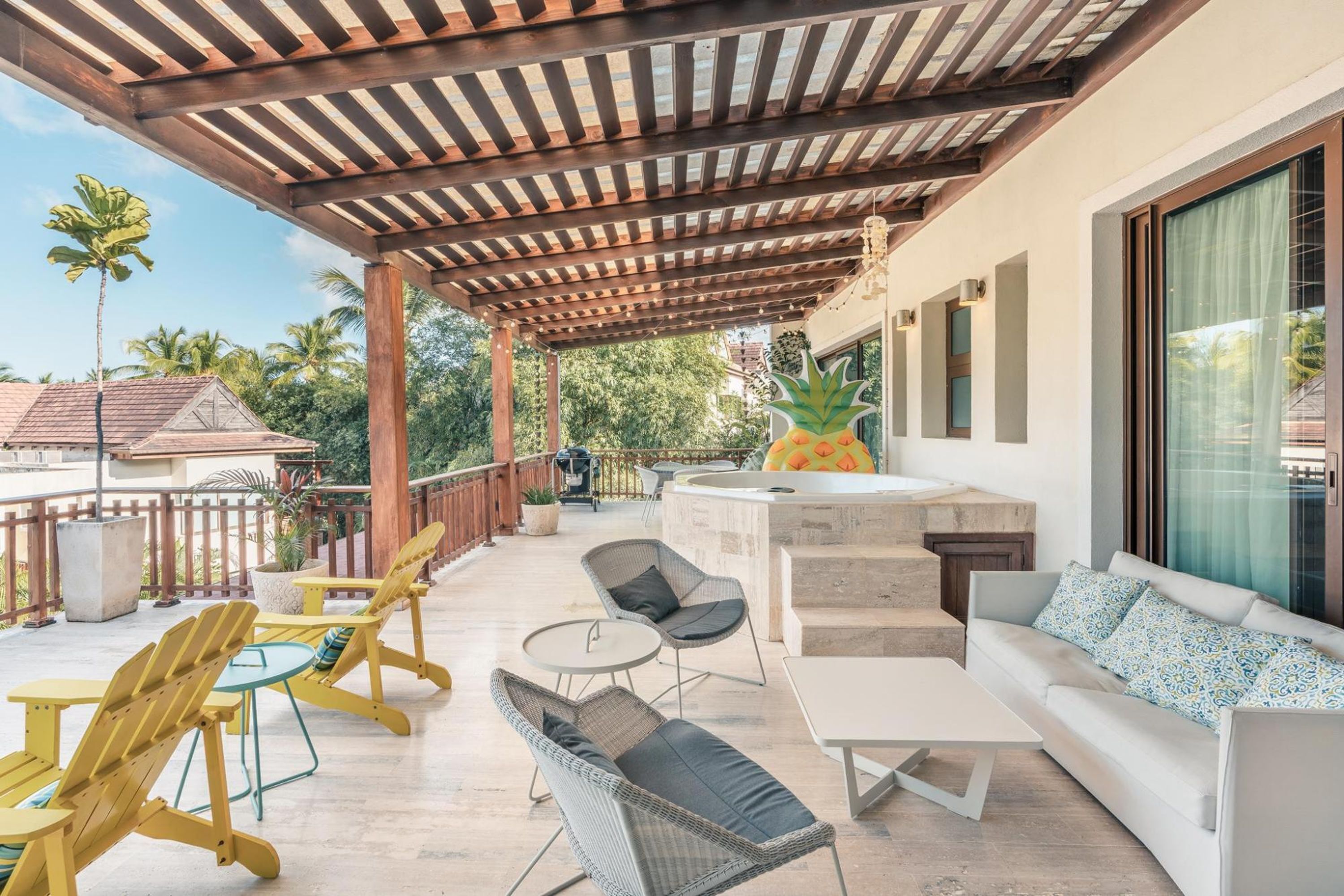 A covered outdoor patio with seating, a bar area, and a view of the surrounding landscape.