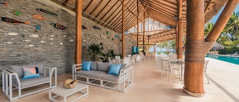 An outdoor lounge area with stone walls, a pool, and seating arrangements.