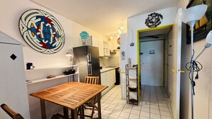 Een kleine keuken met een eethoek, een koelkast, een spoelbak en een kunstwerk aan de muur.