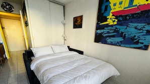 A bedroom with a bed, a nightstand, a lamp, and a painting on the wall. - Studio cabin in Port Argelès with loggia and private parking (Argelès-sur-Mer)