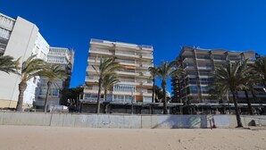 A beachfront hotel with multiple floors, balconies, and palm trees. - Modern 3-bedroom beachfront house, Salou (Salou)
