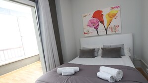A bedroom with a large bed, two pillows, and two rolled towels. There is a window with curtains and a painting on the wall. - Modern 3-bedroom beachfront house, Salou (Salou)