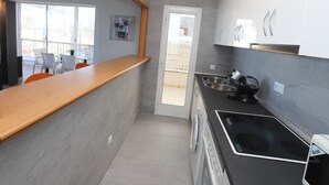 A modern kitchen with grey tiles, a wooden countertop, and a built-in grill. - Modern 3-bedroom beachfront house, Salou (Salou)