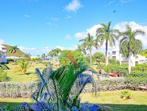 A resort with multiple white buildings, palm trees, and well-maintained lawns.