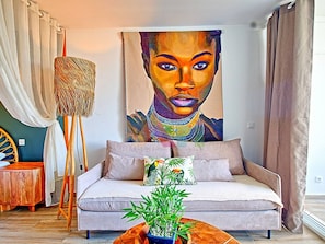 A living room with a sofa, a painting, a lamp, and a plant.