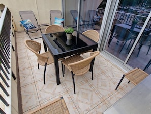 A balcony with a glass table, wicker chairs, and a potted plant. - Charming 2-Room Apartment with Pool, Terrace, and A/C - 4 Sleeps - Near Port and Beach (Port Camargue)