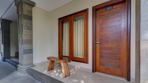 Una puerta de madera con el número 101, un pilar de piedra y un banco de madera frente a un edificio.