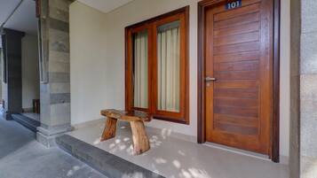 A wooden door with the number 101, a stone pillar, and a wooden bench outside a building.