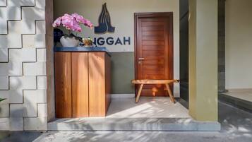 A wooden counter with a vase of pink flowers, a door, and a small bench.
