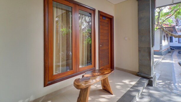 Un pasillo con puertas de madera, un banco y un pilar de piedra.
