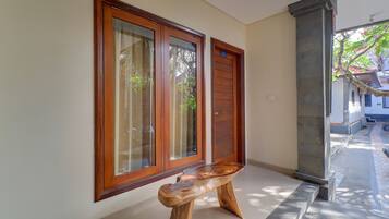 A hallway with wooden doors, a bench, and a stone pillar.