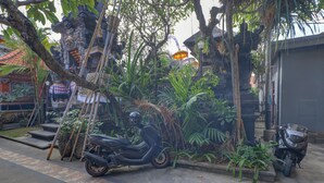 Una moto estacionada en un jardín exuberante con un sendero de piedra y un edificio tradicional al fondo.