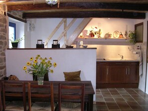 Una cocina rústica con armarios de madera, salpicadero de azulejos y una pequeña isla con un jarrón de flores amarillas.