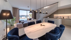 Een moderne eetruimte met een marmeren tafel, blauwe gestoffeerde stoelen en hanglampen.