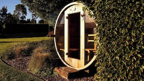 Een ronde houten constructie met een open deur, omringd door groen.