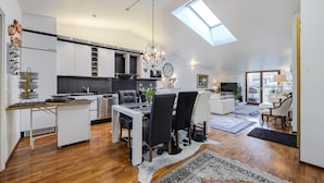 A spacious loft apartment with a kitchen, dining area, and living room. It features a skylight, modern appliances, and a cozy seating area. - Luxus penthouse in great location (Helsinki)