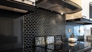 A kitchen with black tiled backsplash, stainless steel appliances, and decorative tiles featuring Parisian landmarks. - Luxus penthouse in great location (Helsinki)