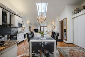 A modern kitchen with a dining area, featuring a chandelier, a large window, and a view of the city. - Luxus penthouse in great location (Helsinki)