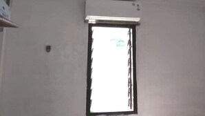 A room with a single window, an air conditioning unit, and a mounted television. - OYO Life 92779 Kost Arjuna (Tangerang)
