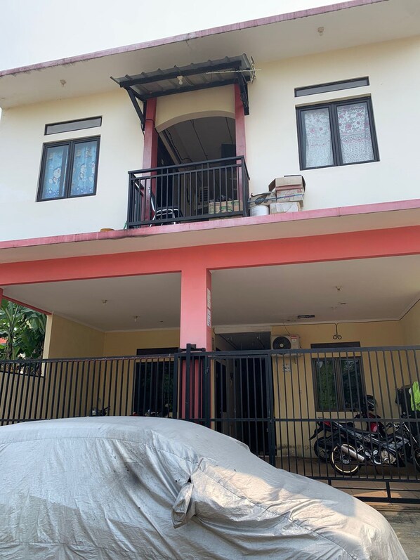 A two-story building with a covered balcony and a covered car. - OYO Life 92779 Kost Arjuna (Tangerang)