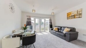 A modern living room with a dining area, a grey sofa, and a painting on the wall. - Spacious One bed, Stratford, Westfields, London (London)