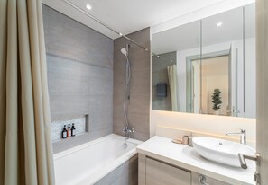 Deluxe appartement | Badkamer | Een bad, een haardroger, handdoeken, toiletpapier